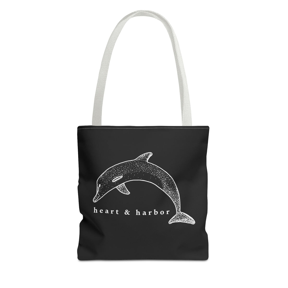 Black tote bag with white handles and original hand-drawn white dolphin artwork by Heart & Harbor