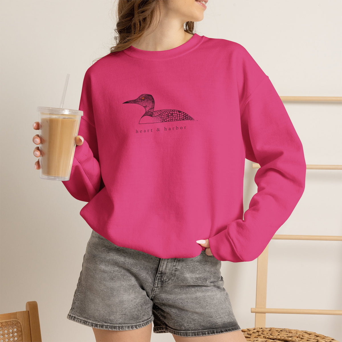 Unisex pink Gildan 18000 crewneck sweatshirt featuring original hand-drawn Heart & Harbor common loon artwork